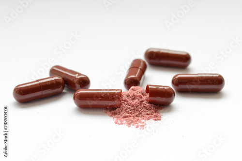 Brown tablets, gelatin capsules, one of them was open and with the poured powder