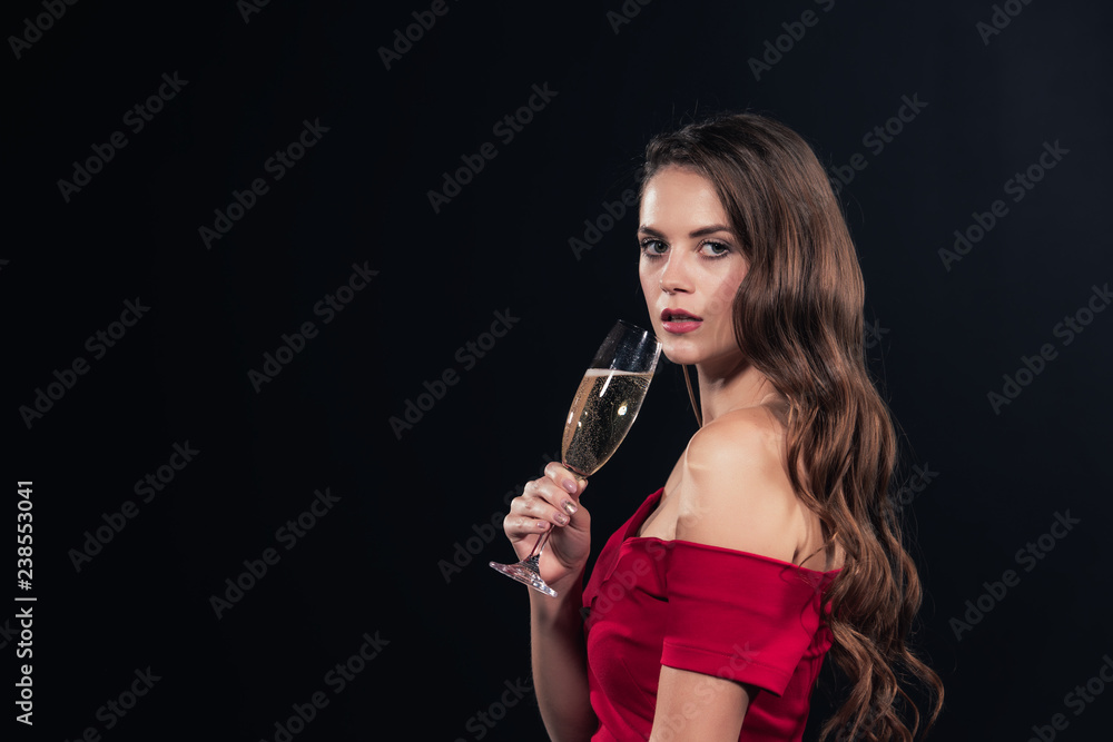 beautiful woman in red dress looking at camera and holding glass of champagne isolated on black beautiful woman in red dress looking at camera and holding glass of champagne isolated on black