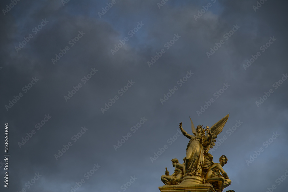 statues opéra de Paris pointant vers un ciel orageux