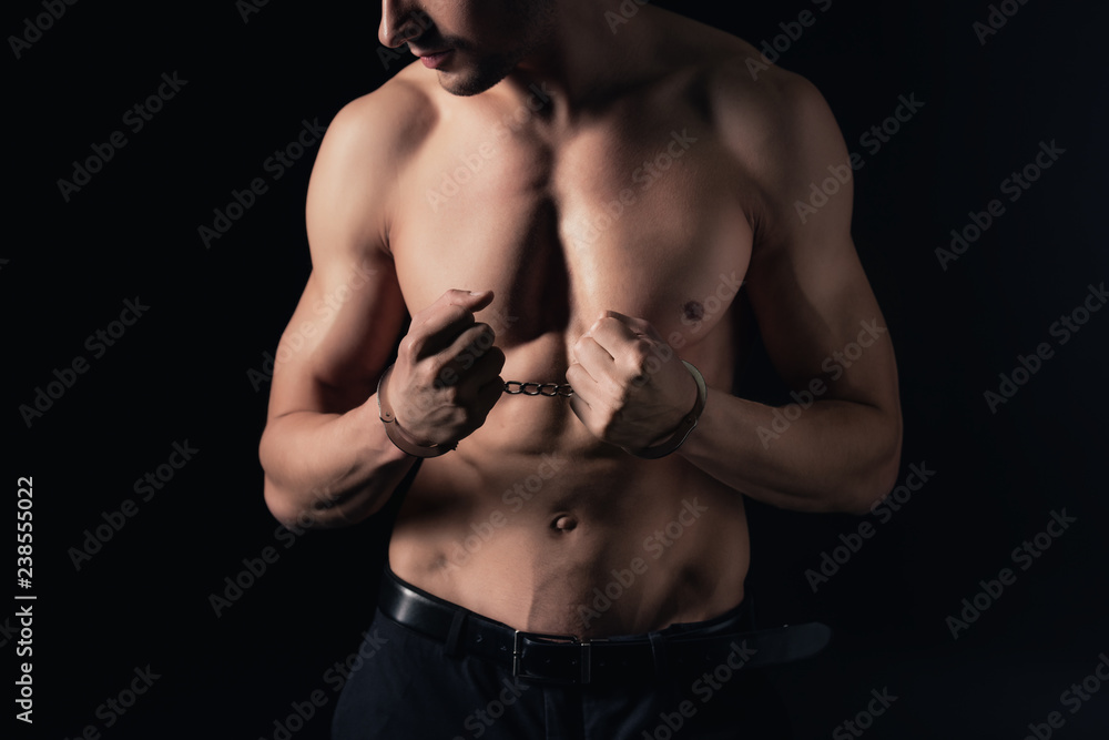 Fototapeta premium cropped view of shirtless man in handcuffs isolated on black