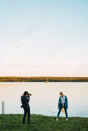 Young man taking pictures of young woman at a lake photo