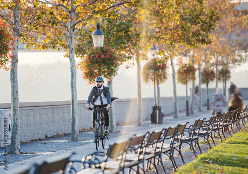 Hipster businessman commuter with bicycle traveling home from work in city. photo