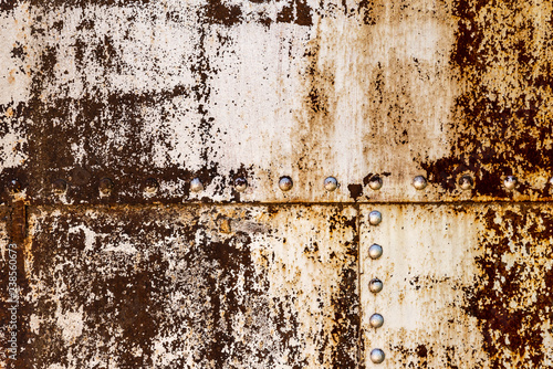 Textured rusted sheet of metal with a lot of bolts