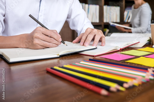 High school or college student group sitting at desk in library studying and reading, doing homework and lesson practice preparing exam to entrance, education concept