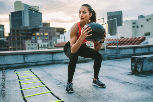 Female athlete doing squats holding a medicine ball