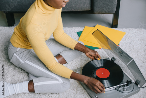 cropped view of african american woman using record player on carpet