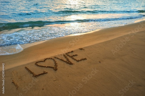 Valentines day concept  love heart shape handwriting on sand beach in sunrise and blue ocean.