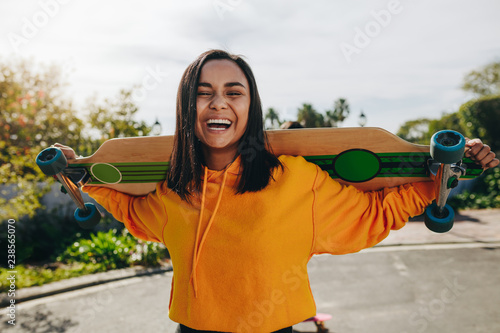 Girl standing in street with a longboard photo