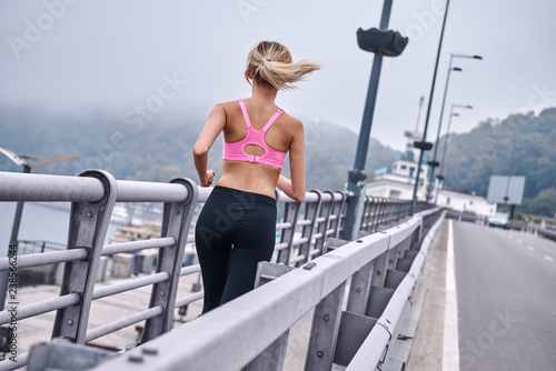 Morning workout. Close up rear view of young womanin sports clothing jogging while exercising outdoors © Friends Stock