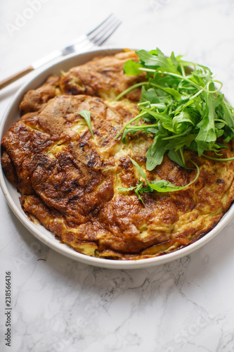 Tortilla omelette with sliced potatoes and herbs on marble table