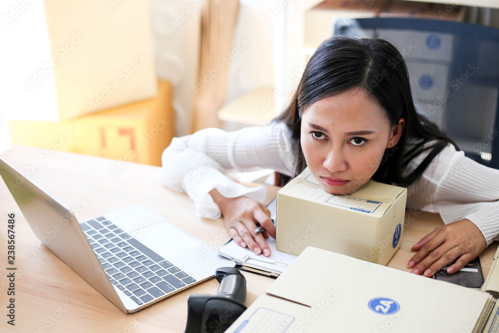 Tired unhappy of Young asian girl is freelancer Start up small business owner writing address on cardboard box at workplace,Shipping shopping online small business entrepreneur SME or freelance Tired unhappy of Young asian girl is freelancer Start up small business owner writing address on cardboard box at workplace,Shipping shopping online small business entrepreneur SME or freelance