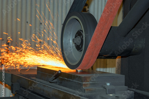 Sparks fly from the work of a belt sander in the workshop. Bokeh effect.