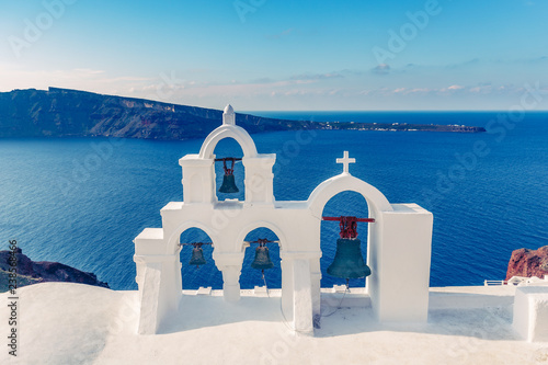 Church bells in Oia village, Santorini island in Greece, on a sunny day with dramatic sky. Scenic travel background.