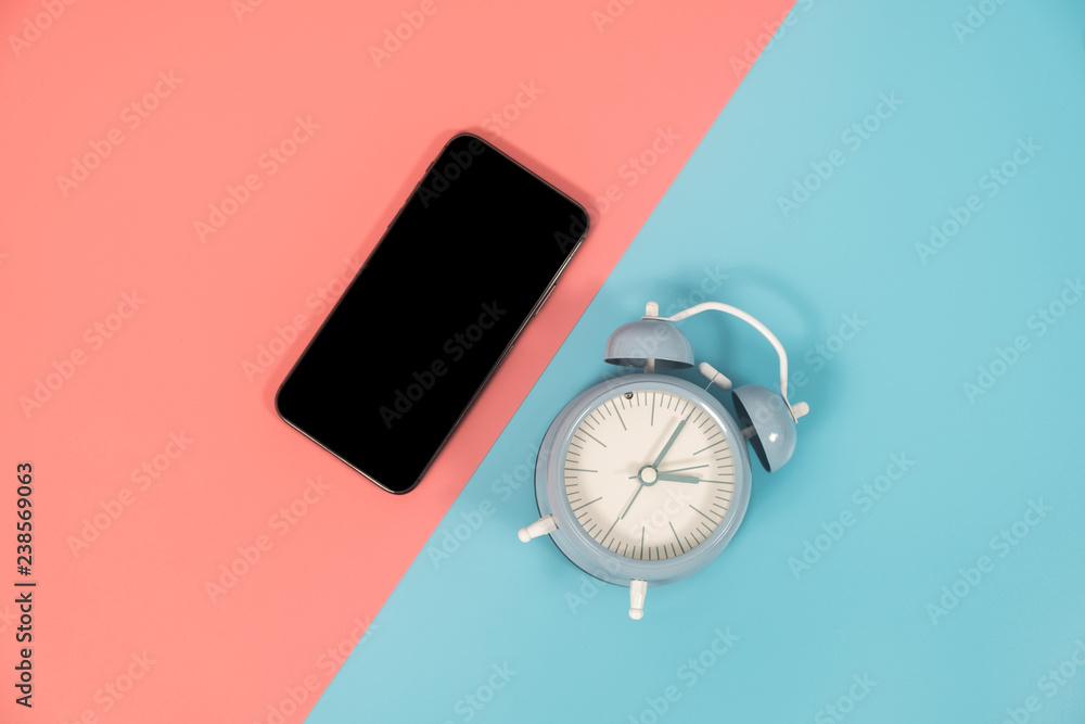Smartphone and clock on colorful background with copy space. Flat lay modern and minimal style. Smartphone and clock on colorful background with copy space. Flat lay modern and minimal style.