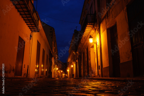 deserted alley with reflections of light on the cobblestone pavement at dusk in Havana