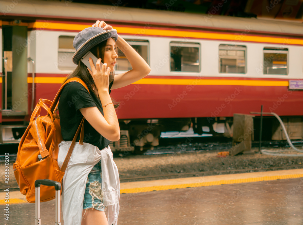 travel concept.beautiful traveller girl in train station.Backpacker pretty woman wear hat talk with smartphone waiting friend in last minute.Passengers are journey traveling and sightseeing by train.