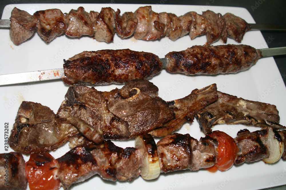 Pork and mutton shashlik on skewers, lulah kebab and lamb ribs served on ungarnished plate