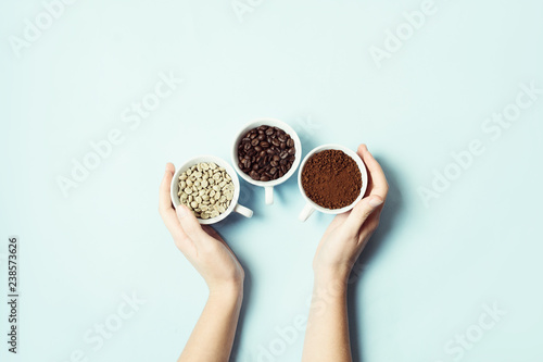 Different types of coffee - ground, grain and unroasted on blue pastel background