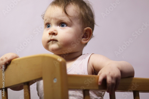 Cute baby girl of 9 months in children's bed.