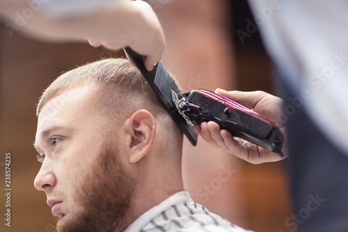 Barber shaves the client's head with a shaving machine.