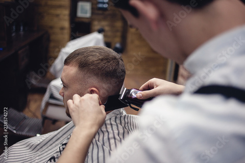 Barber shaves the client's head with a shaving machine.