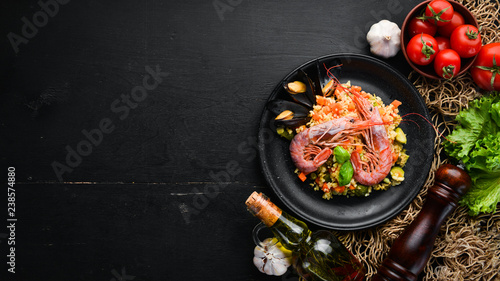 Bulgur with shrimp, mussels and vegetables. On the old background. Top view. Free space for your text.