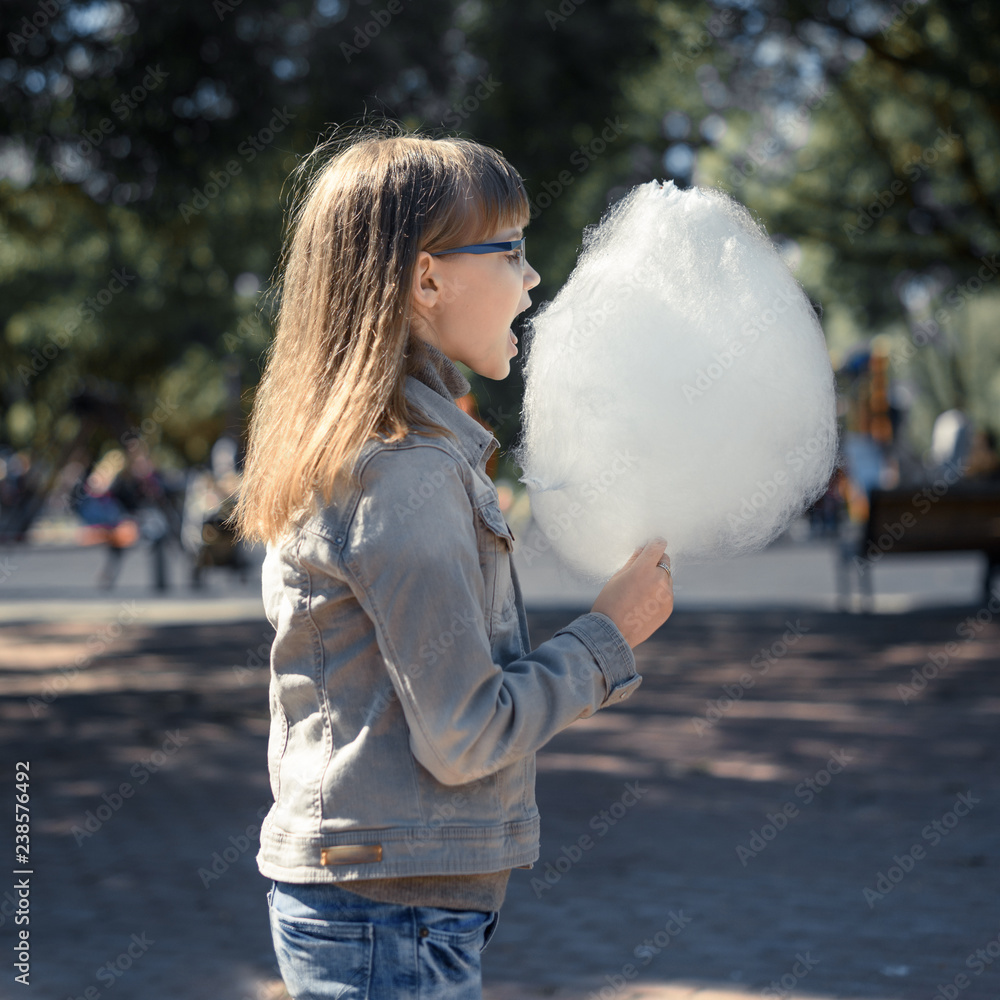 Happy teenager girl eating cotton candy in the Park. Happy teenager girl eating cotton candy in the Park.