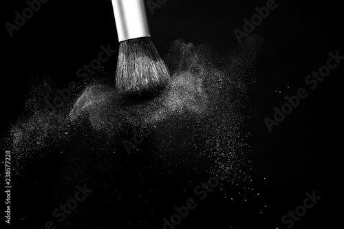 white powder splash and brush for makeup artist or beauty blogger in black background