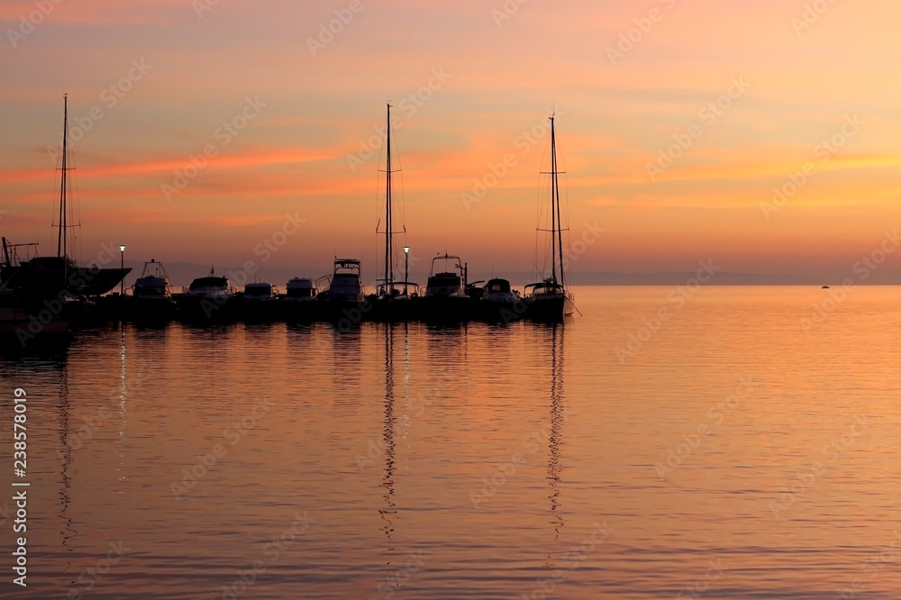 Boats in a harbor at sunset with beautiful colorful sky.
