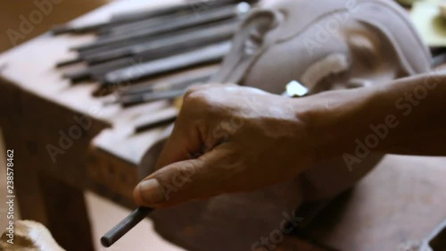 A cambodian artist is carving up a wood figure of buddha MF