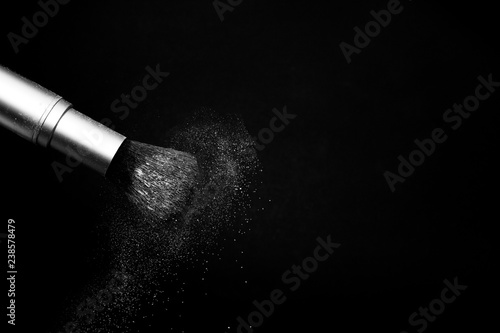 white powder splash and brush for makeup artist or beauty blogger in black background
