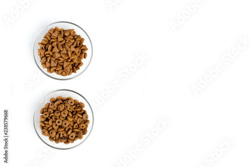 Dry cat food poured into a glass bowl on a white background.
