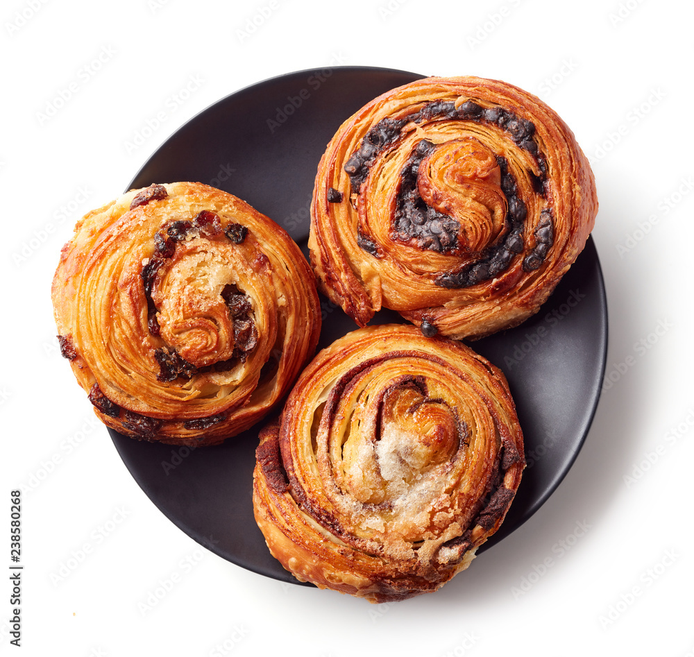 Fototapeta premium Sweet buns on black plate isolated on white, from above