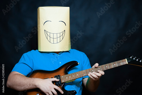 Emotion concept. A man plays the guitar. Looking at the lens. The facial expression is cheerful and playful.