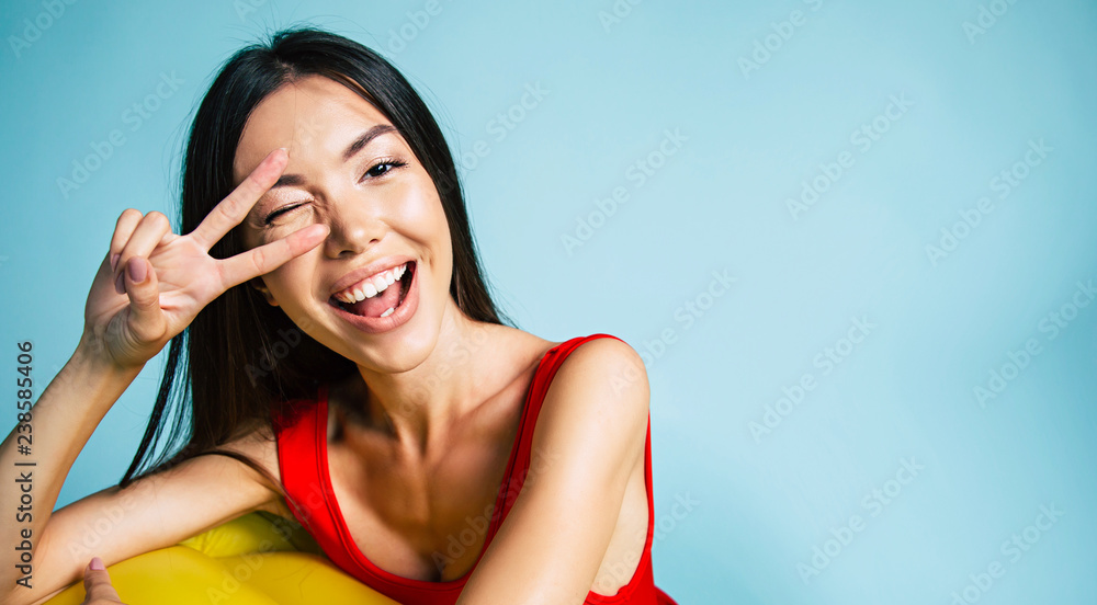 Fototapeta premium Beautiful lovely Sexy woman standing on blue background in swimsuit or bikini and smiling while posing. Summertime and vacation