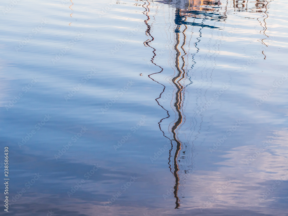 Reflection of a boat mast in the port of Olhao, Algarve region in south of Portugal, at sunset