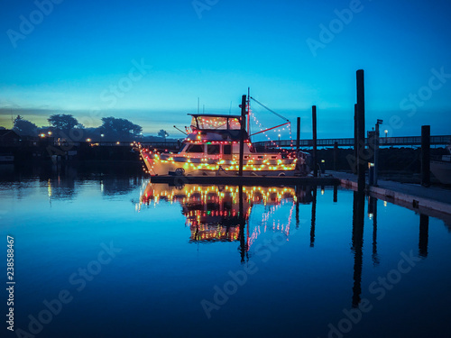 Boat in a harbor decorated with colorful christmas lights 