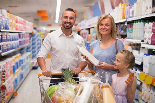 Family selecting shampoo in supermarket.