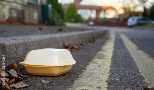 Discarded food container in gutter by the side of the road