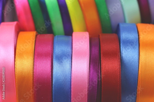 A lot of beautiful colored satin ribbons top view for decoration, gift wrapping and sewing in a fabric shop bright and colorful background close up
