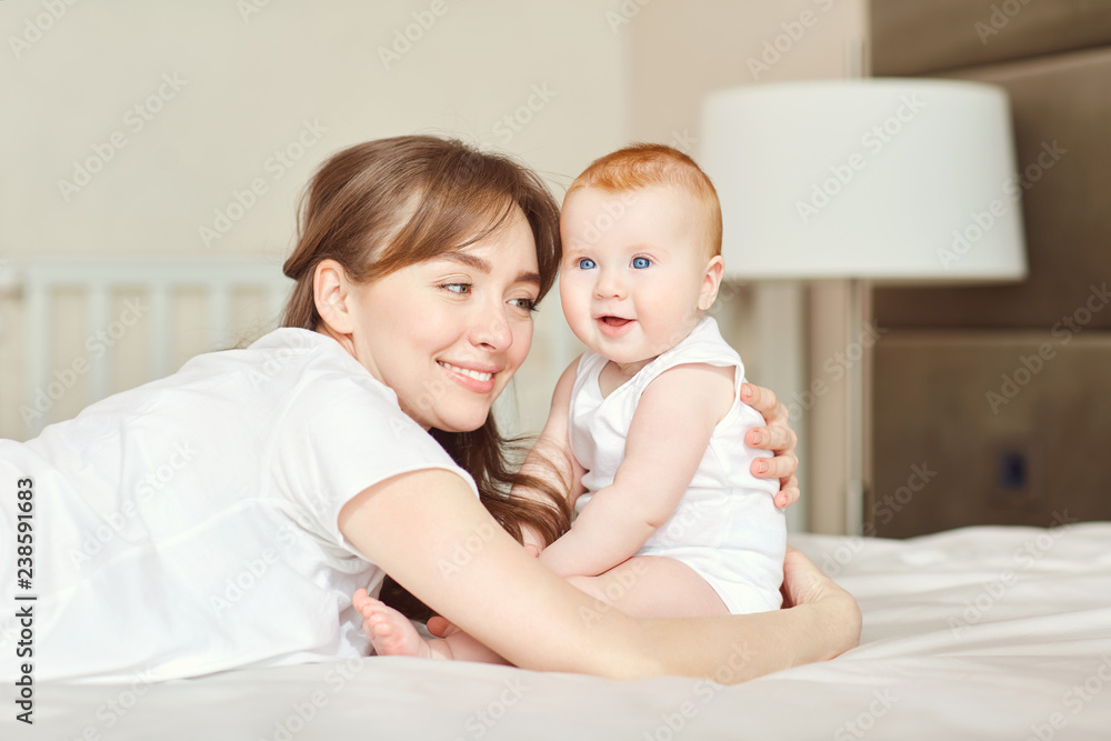 Mother playing with baby on the bed. 