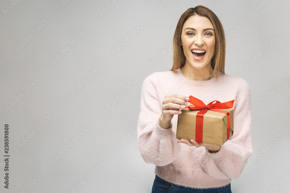 Image of Happy brunette woman in casual holding gift box and looking at the camera isolated over white background. Image of Happy brunette woman in casual holding gift box and looking at the camera isolated over white background.