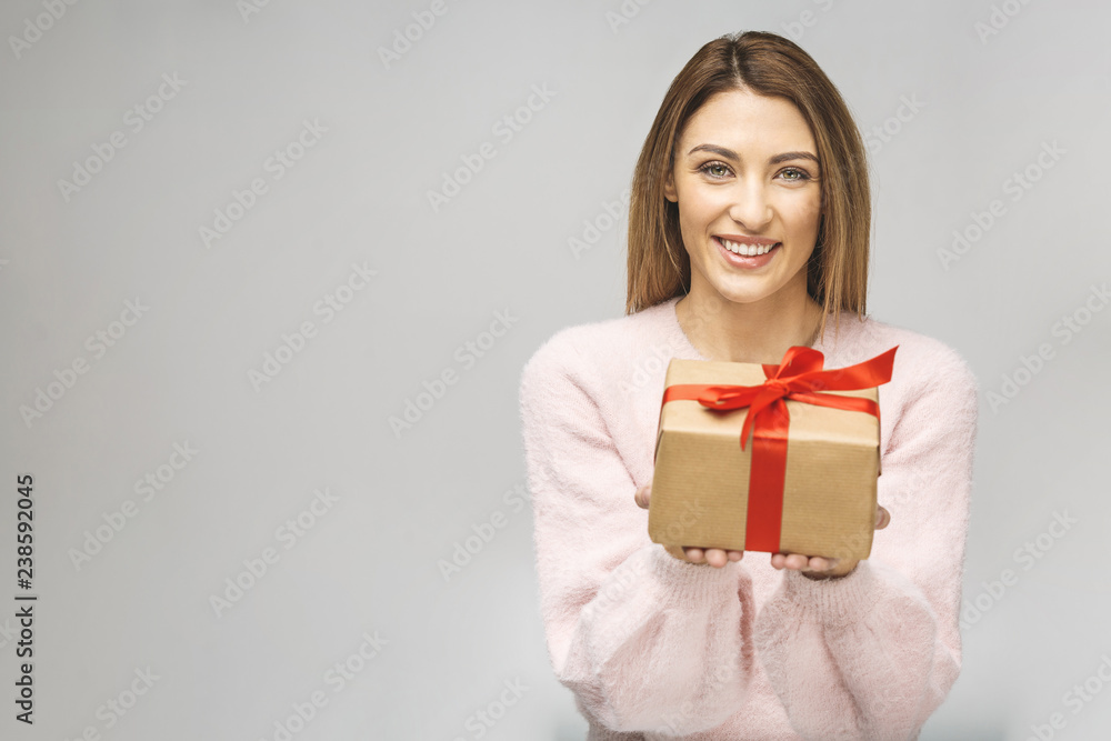 Image of Happy brunette woman in casual holding gift box and looking at the camera isolated over white background. Image of Happy brunette woman in casual holding gift box and looking at the camera isolated over white background.