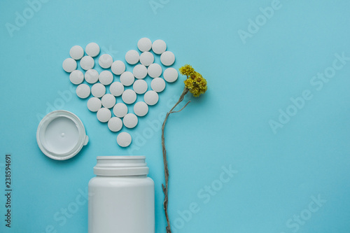 Medicines white, round heart shaped pills isolated on blue background.