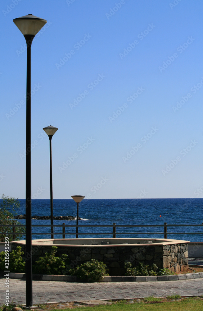 Three street lamps on a sea promenade with sea and sky on the background