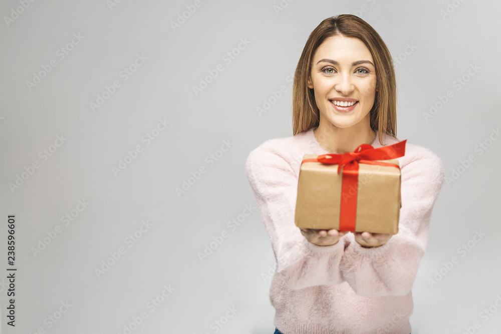 Image of Happy brunette woman in casual holding gift box and looking at the camera isolated over white background. Image of Happy brunette woman in casual holding gift box and looking at the camera isolated over white background.