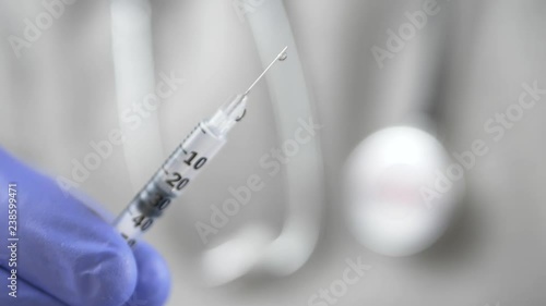 A doctor with a phonendoscope and blue gloves offers a syringe with a vaccine or a medicine photo