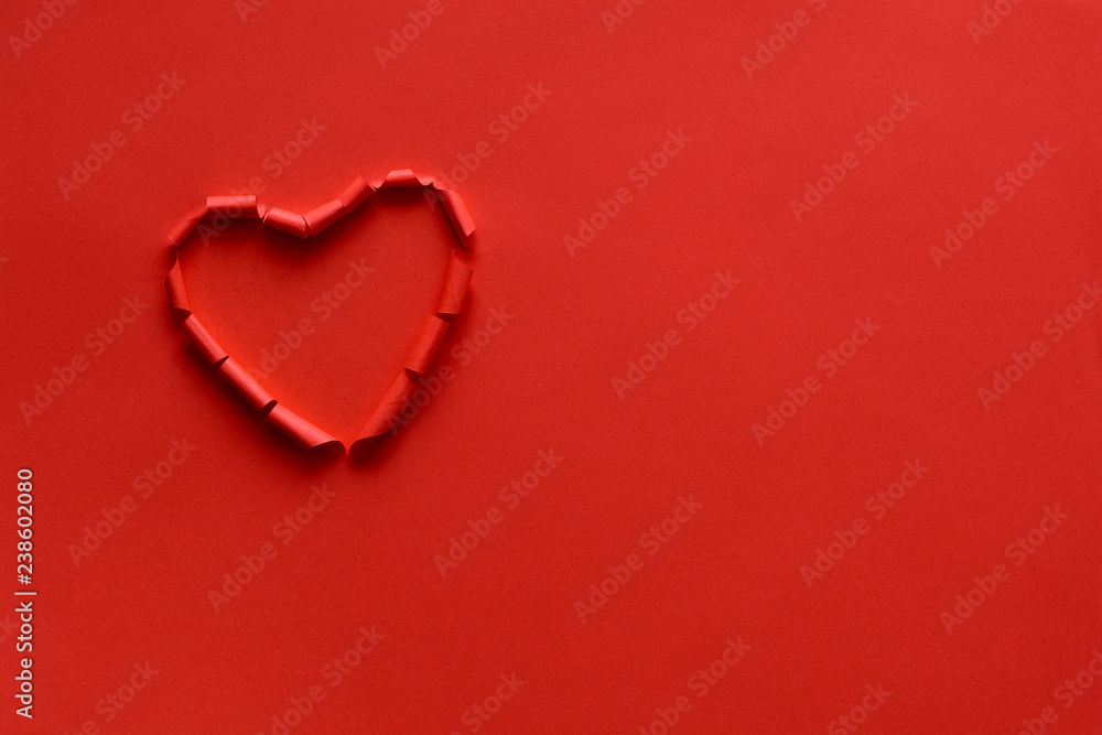 Ripped paper hole heart shaped on red paper background. Valentine's day celebration concept