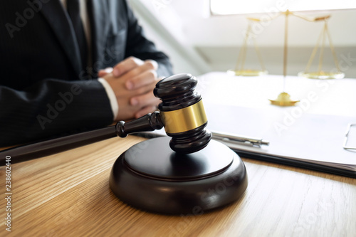 Legal law, advice and justice concept, male lawyer or notary working on a documents and report of the important case and wooden gavel, balance on table in courtroom