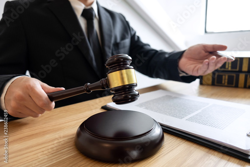 Legal law, advice and justice concept, male counseling lawyer or notary working on a documents and contract papers of the important case and wooden gavel, brass scale in courtroom